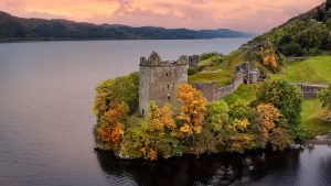 Read more about the article Aerial view of Urquhart Castle at Loch Ness at autumn sunset, Scotland, UK