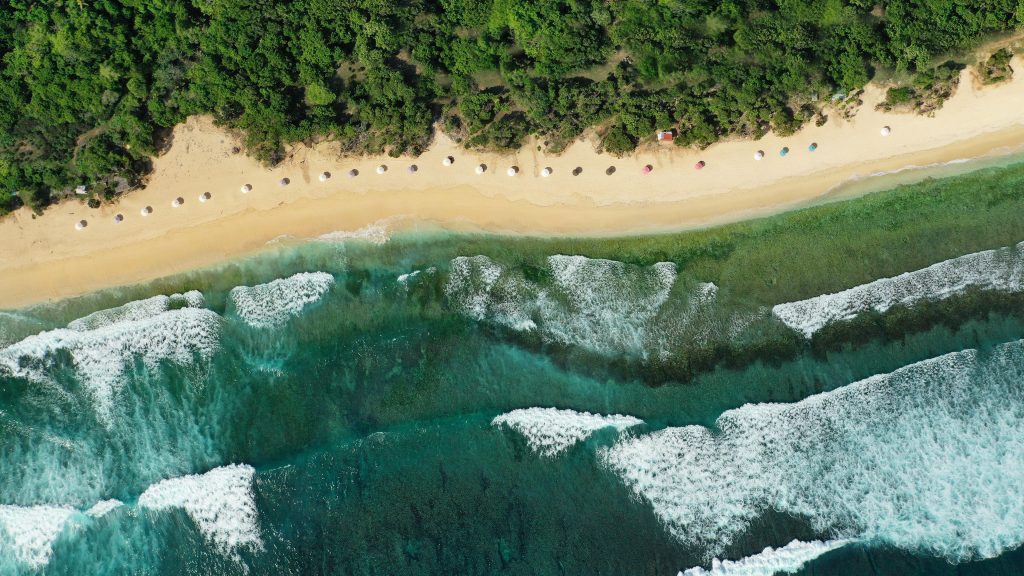 Drone aerial view of beautiful tropical sandy beach with long waves, Bali, Indonesia