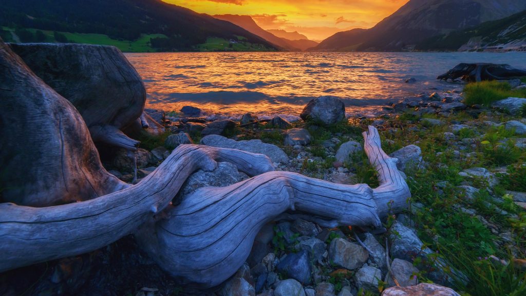 View of Lake Reschen with  dramatic sky and colorful sunset, South Tyrol, Italy