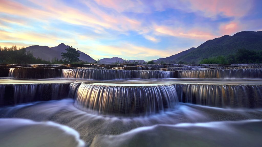 Stepped waterfall group at sunrise in pink sky, Huyuan, China