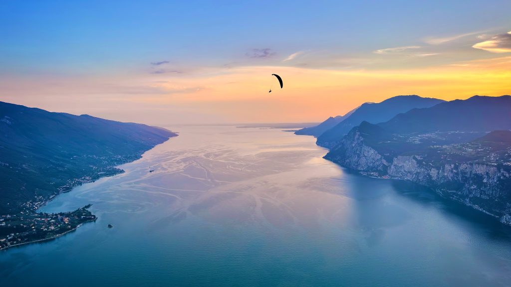 Areal view of Lake Garda with paraglider in front of sunset, Italy