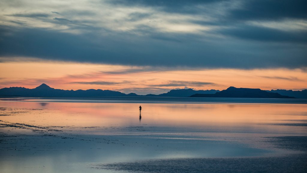 Silhouette person standing on Bonneville Salt Flats against cloudy sky, Utah, USA